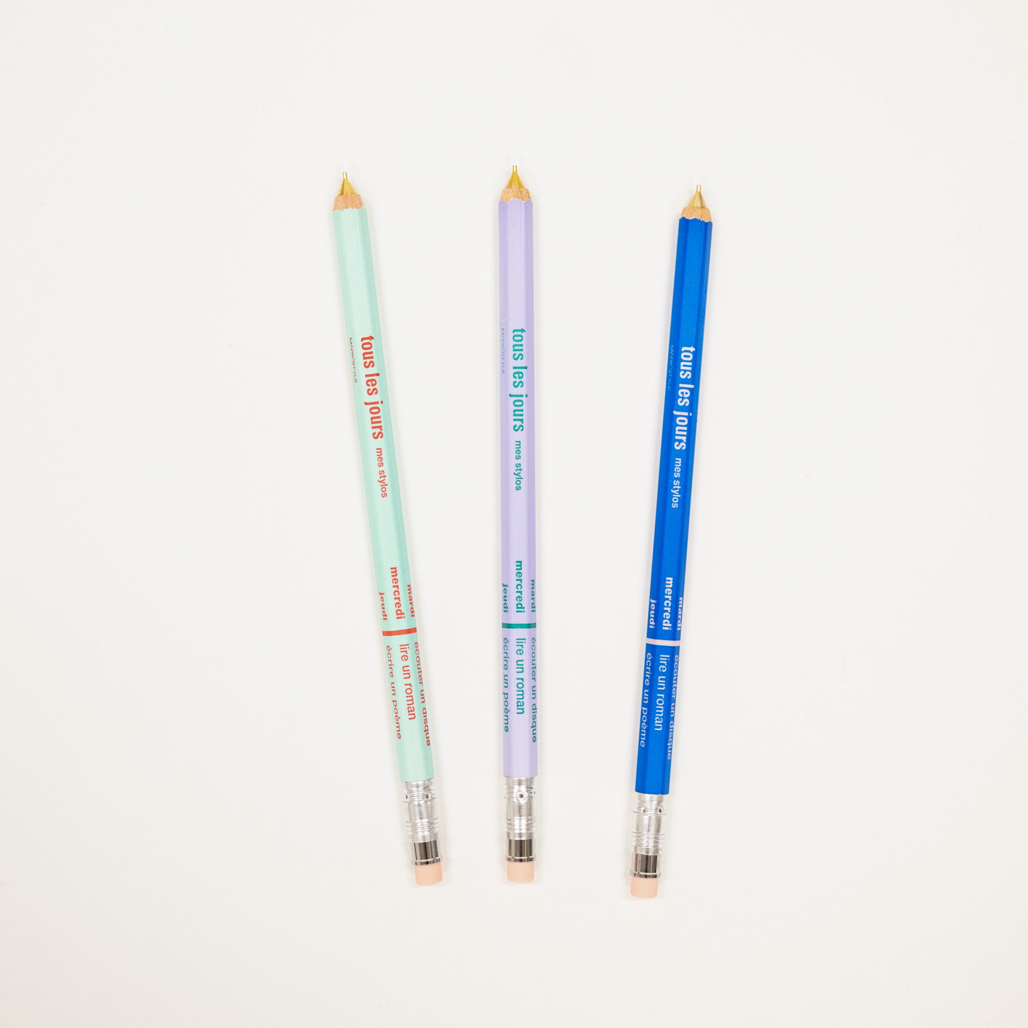 Three colored pencils in green, purple, and blue on a white background