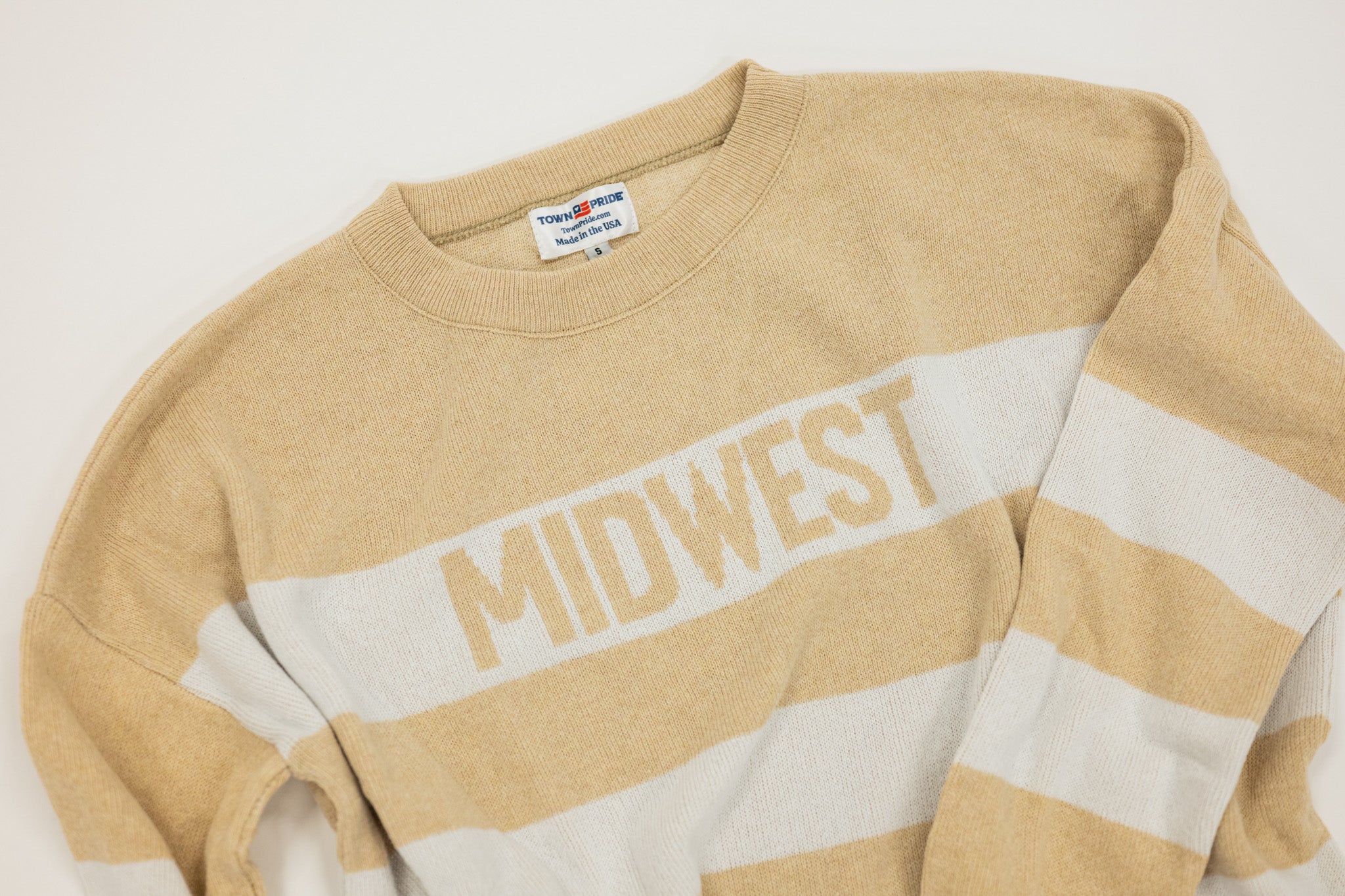 Beige and white striped sweater with 'MIDWEST' text on a light gray background