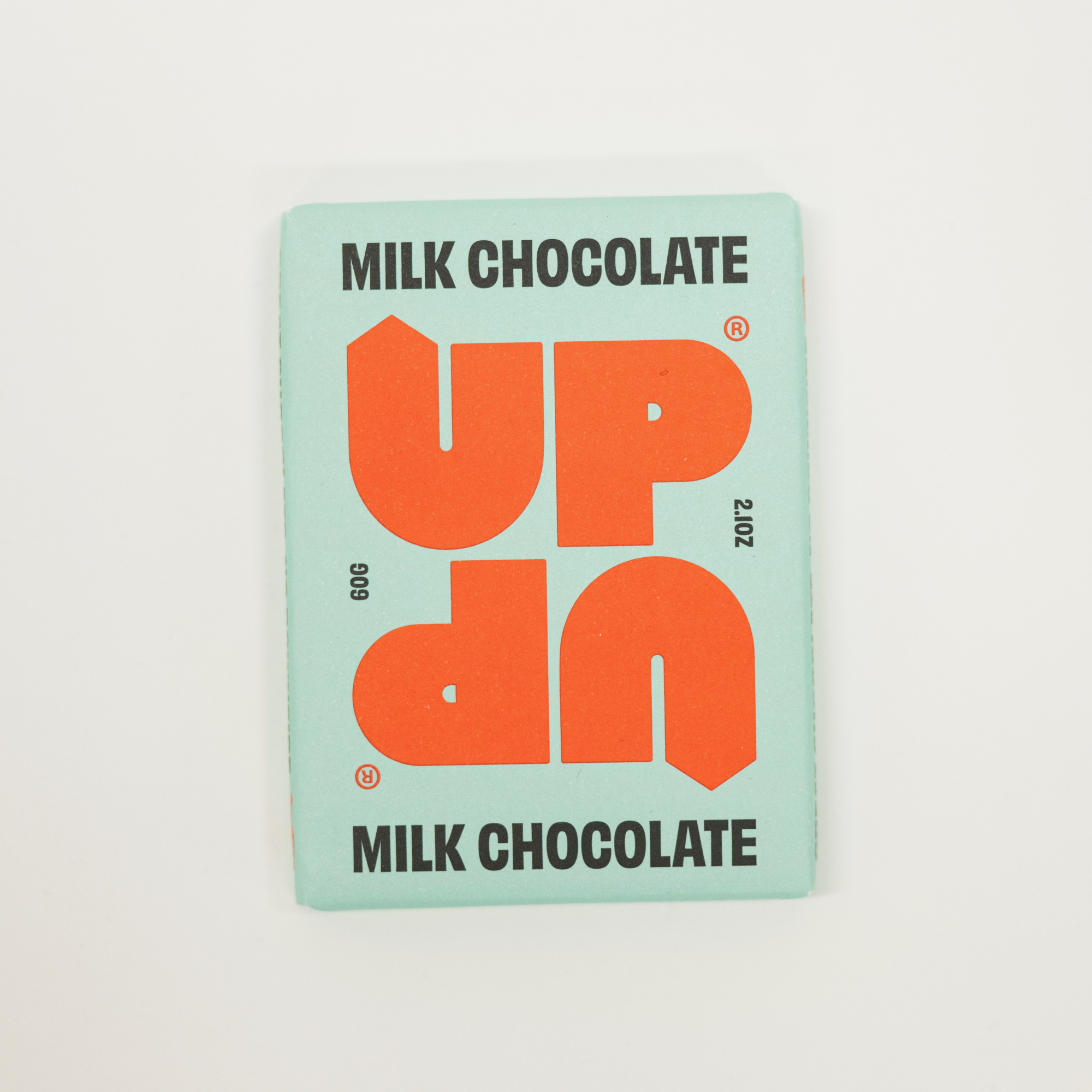 Milk chocolate bar packaging with 'UP' branding on a light gray background