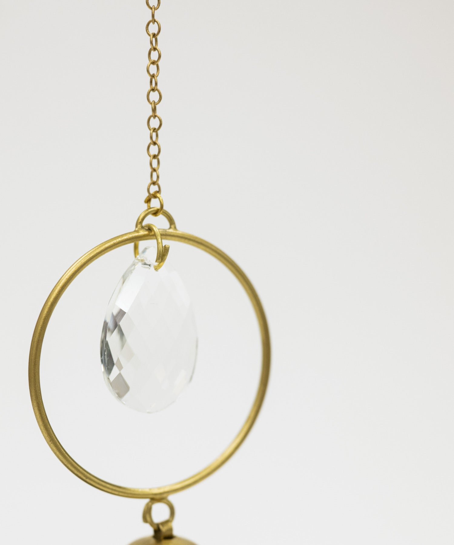 Decorative hanging item with gold frame and clear teardrop on a white background