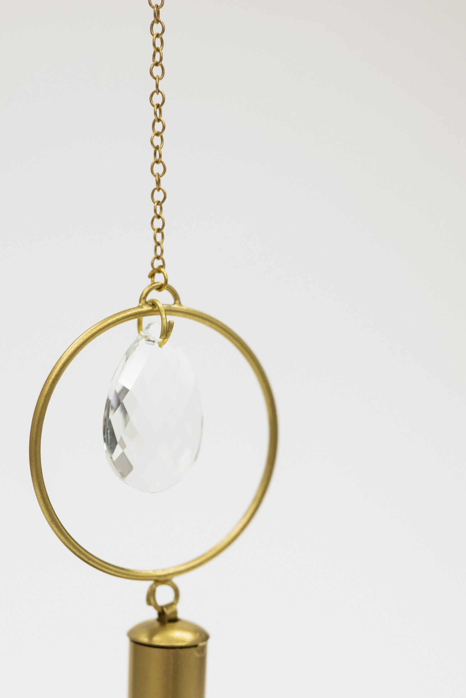 Decorative hanging item with gold frame and clear teardrop on a white background