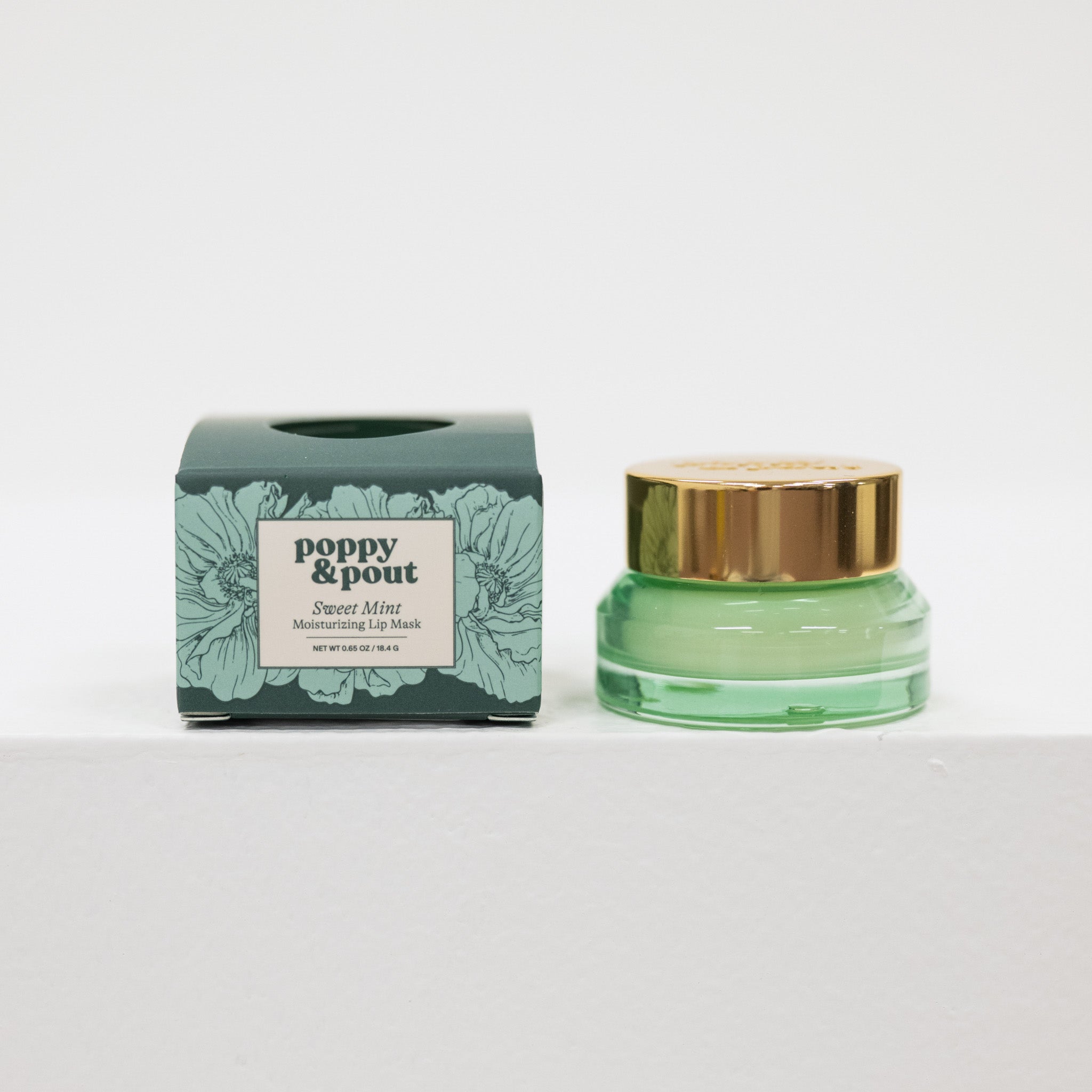 Green lip balm jar with gold cap and matching box on a white background