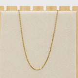 Gold chain necklace on a beige cushion with a wooden base