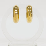 Lightweight gold hoop earrings on a clear stand against a white background