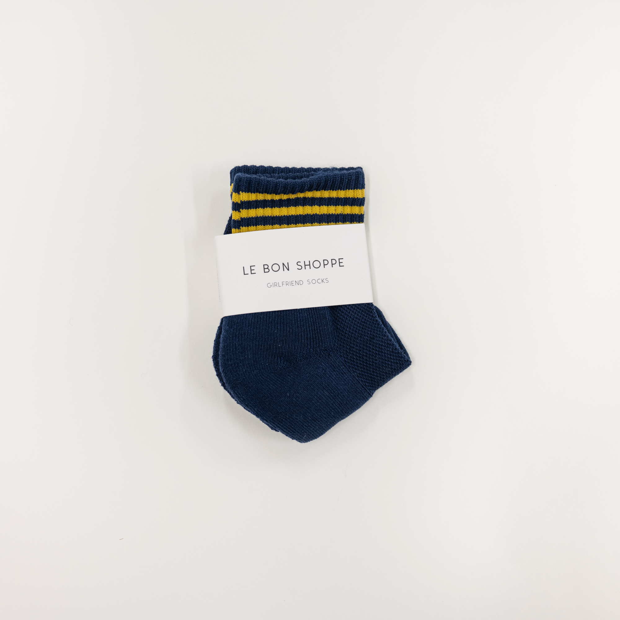Navy blue sock with yellow stripes on a white background, featuring 'Le Bon Shoppe' branding.