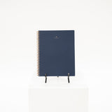a navy linen covered workbook with brass coil binding