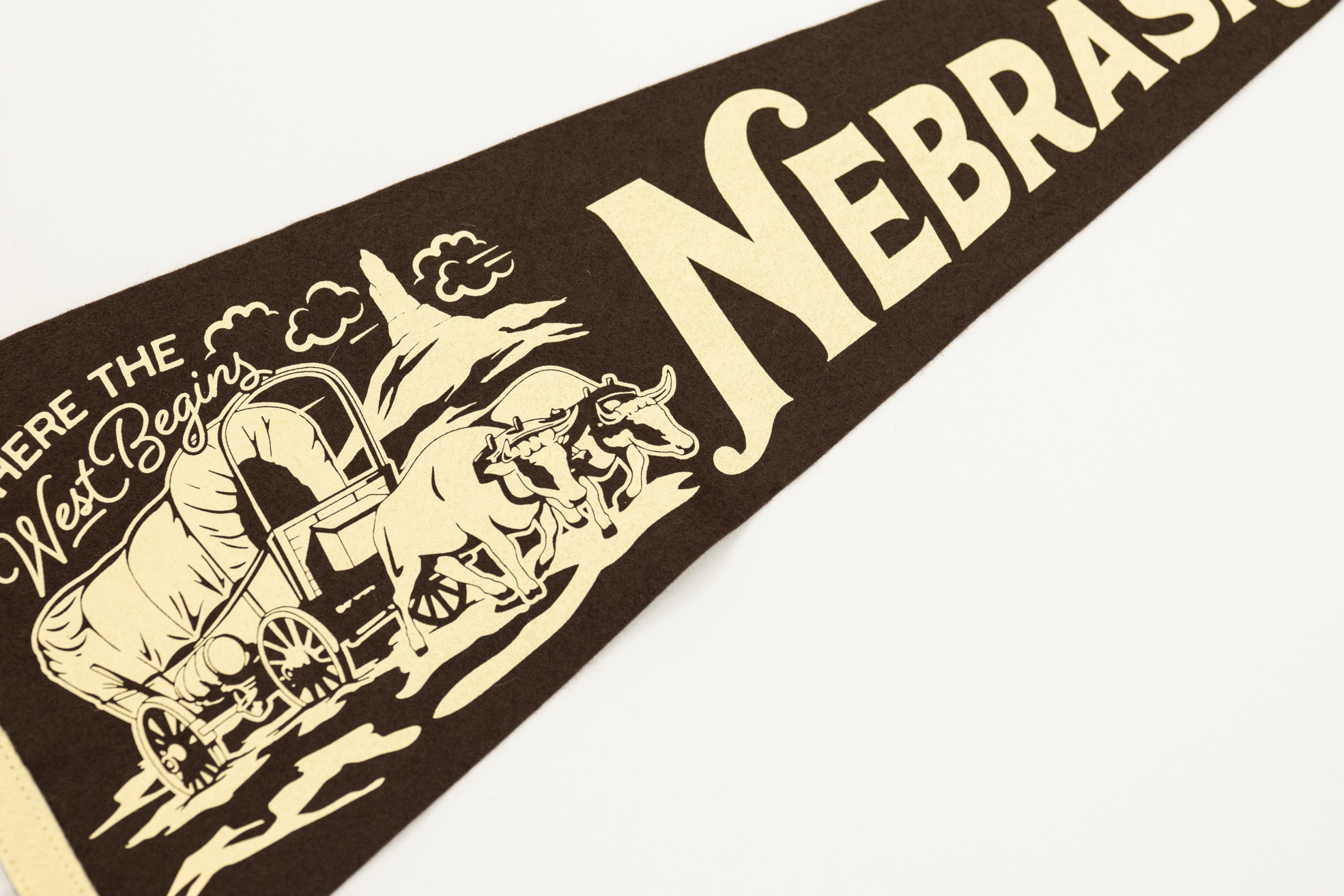 Nebraska-themed decorative banner with a horse, wagon, and cow on a brown background.