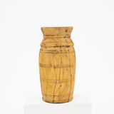 A hand-carved wooden vase with a natural light brown wood grain and dark engraved lines, displayed on a white pedestal against a white background.