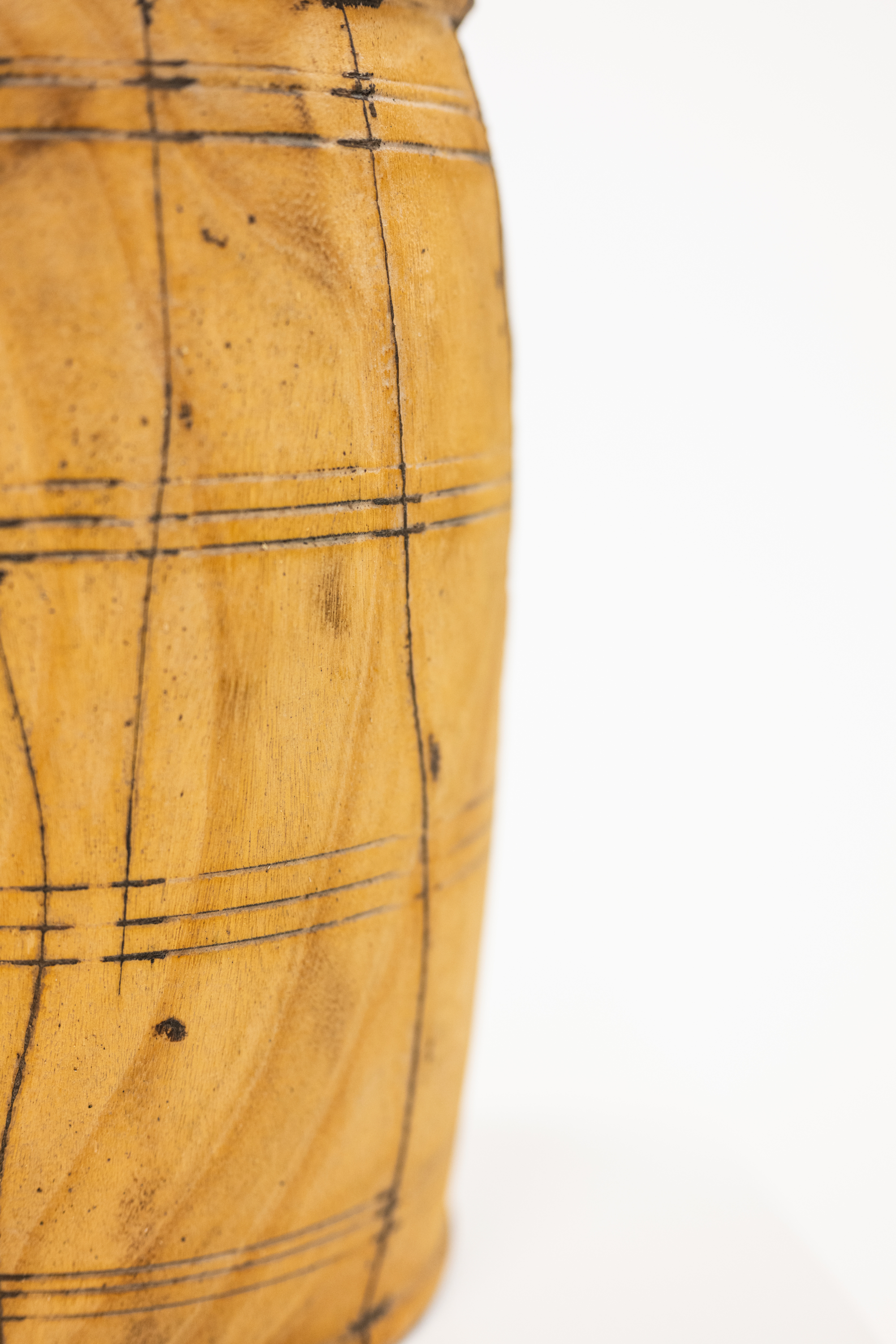 A close-up of a light brown wooden object with dark engraved grid lines, shown against a plain white background.