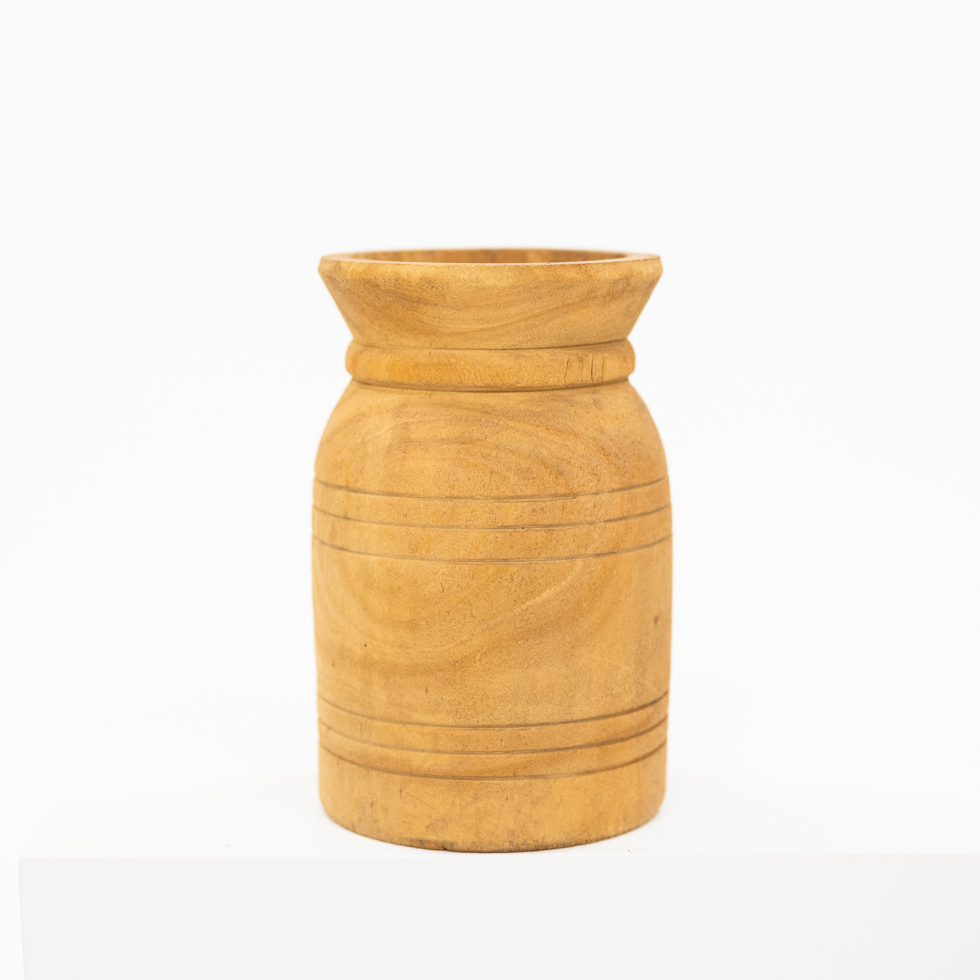 A small cylindrical wooden vase with a flared rim and carved horizontal grooves, shown on a white background.