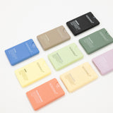 Nine refillable hand sanitizers in assorted pastel and neutral colors, arranged in a loose circle on a clean white background. The bars have a matte finish and a small cutout on one end.