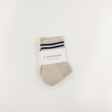 Beige sock with blue stripes and a white label on a light beige background