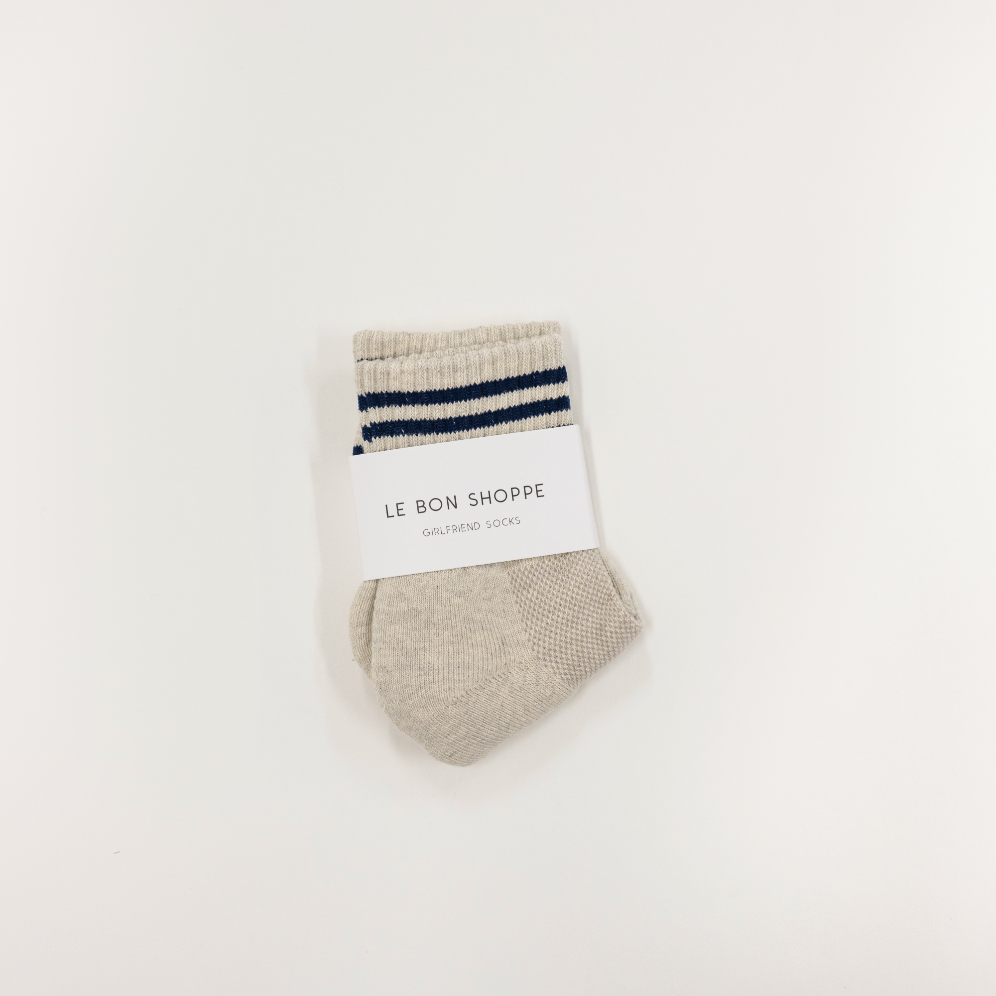Beige sock with blue stripes and a white label on a light beige background