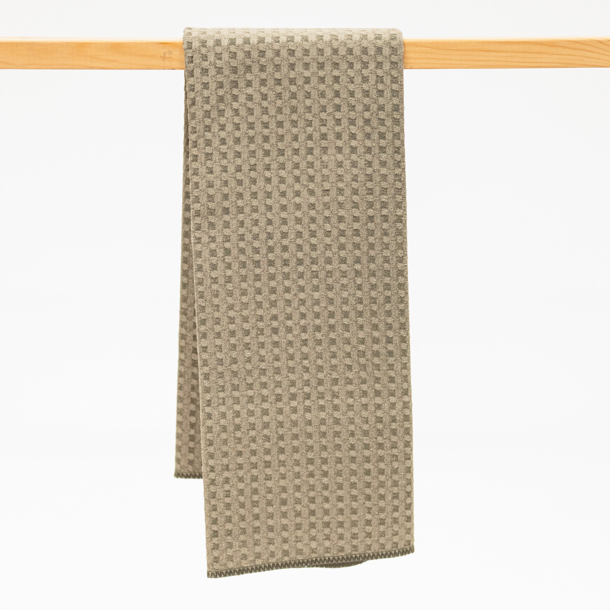 Olive Green textured towel hanging on a wooden rack against a white background