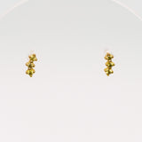 Pair of gold earrings with olive green gems on a white background
