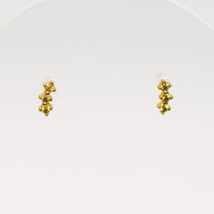 Pair of gold earrings with olive green gems on a white background