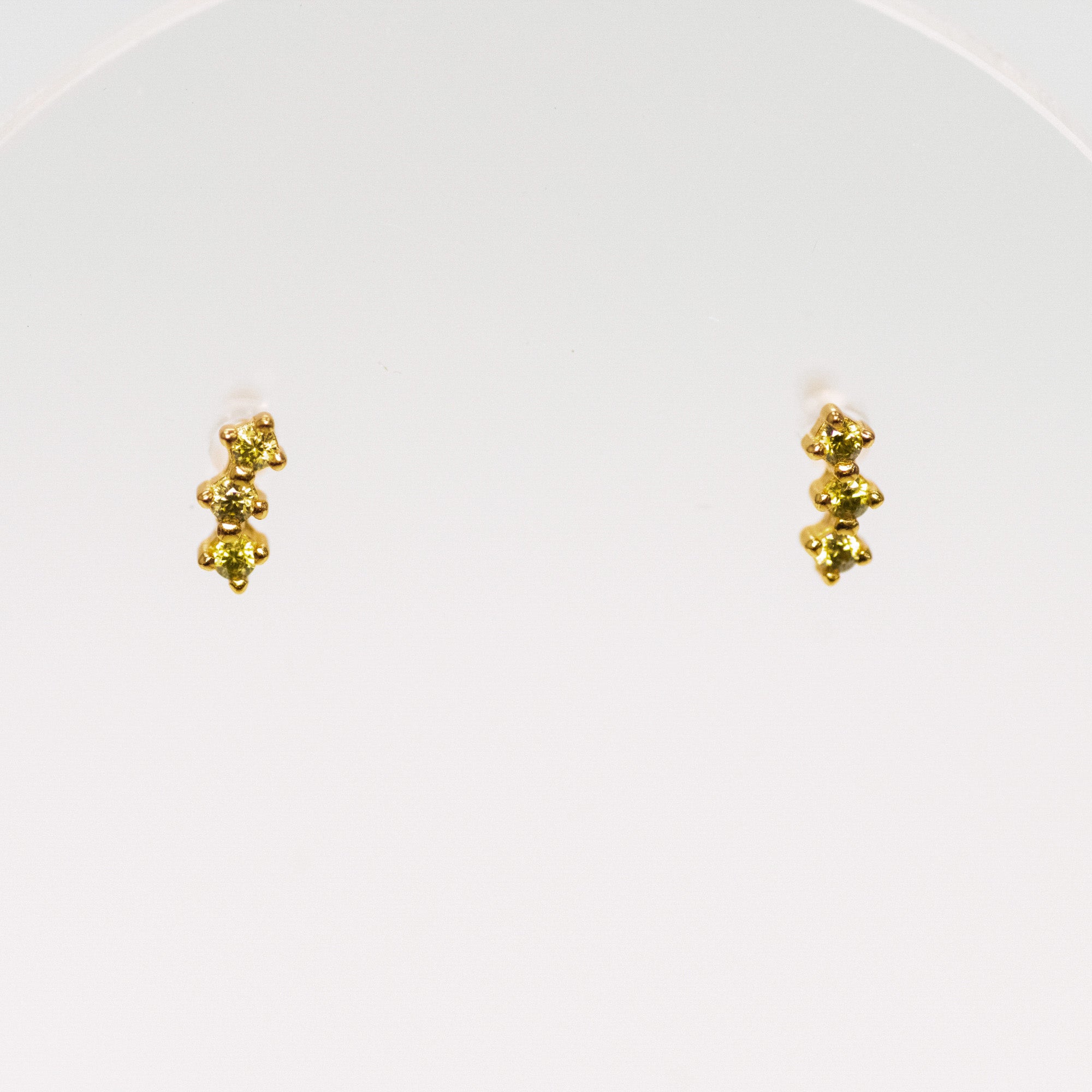Pair of gold earrings with olive green gems on a white background