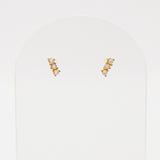 Pair of gold and pearl stud earrings on a light gray background