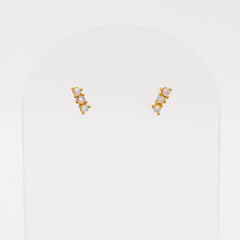 Pair of gold and pearl stud earrings on a light gray background