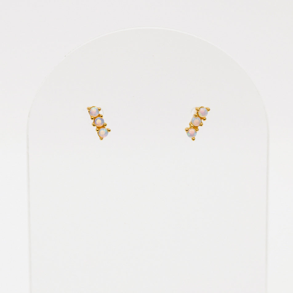 Pair of gold and pearl stud earrings on a light gray background