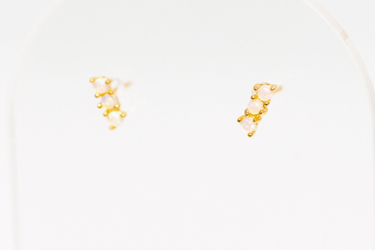 Gold and opal earrings on a white background
