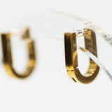 Gold hoop earrings on a clear stand with a blurred background