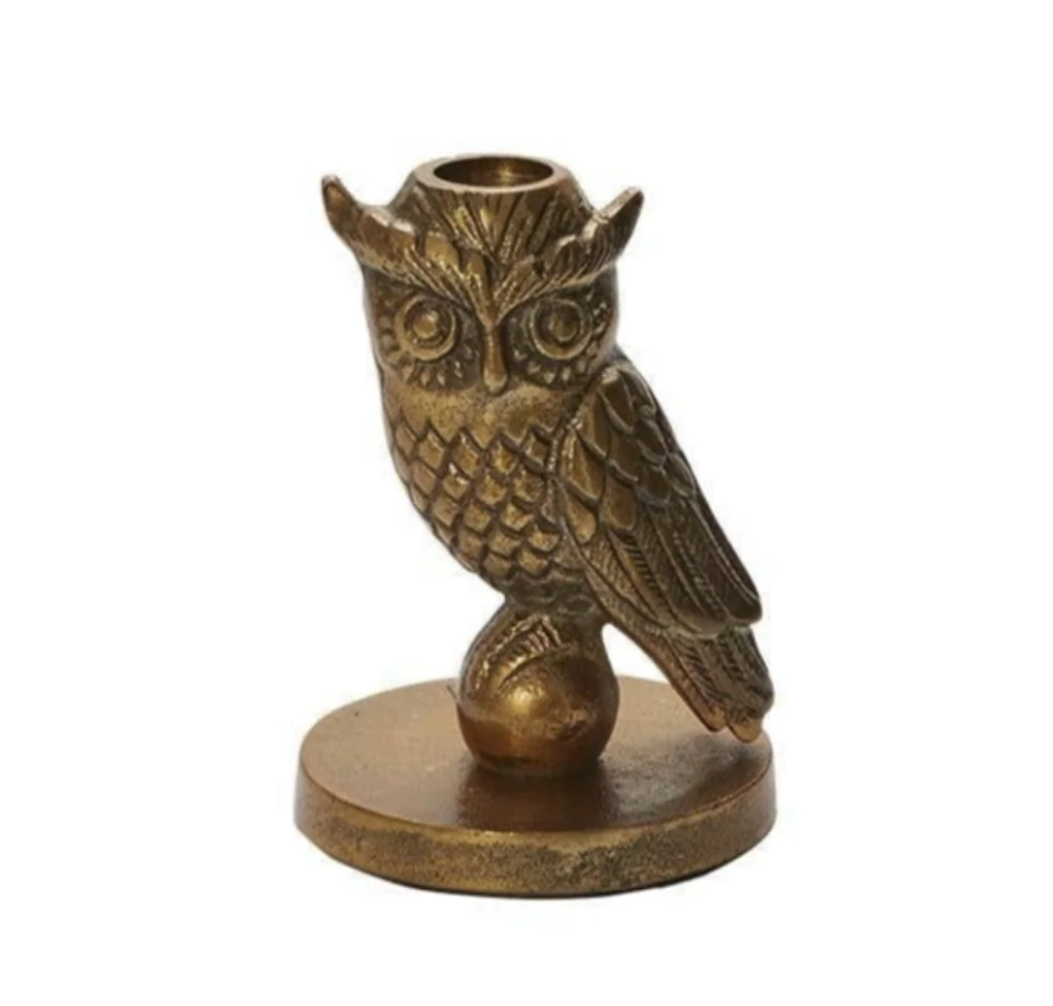 An antique bronze owl figurine perched on a small round base, designed as a candle holder with a circular cup on its head, set against a plain white background.