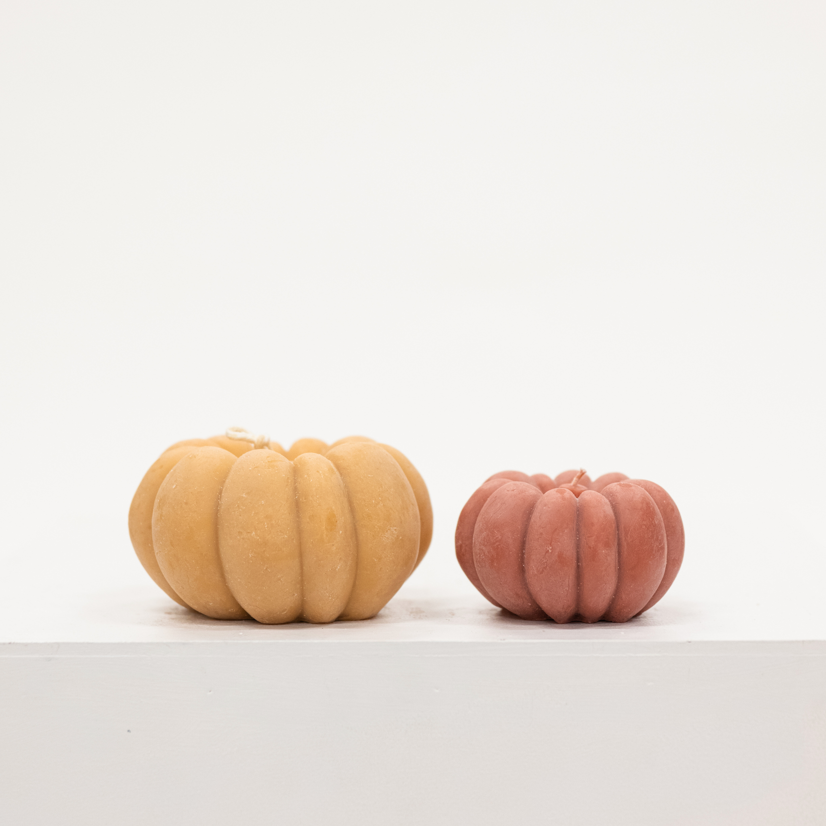 pair of pumpkin shaped candles in light orange and terracotta orange