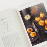 Open cookbook showing a page with a photograph of pastries on a white surface