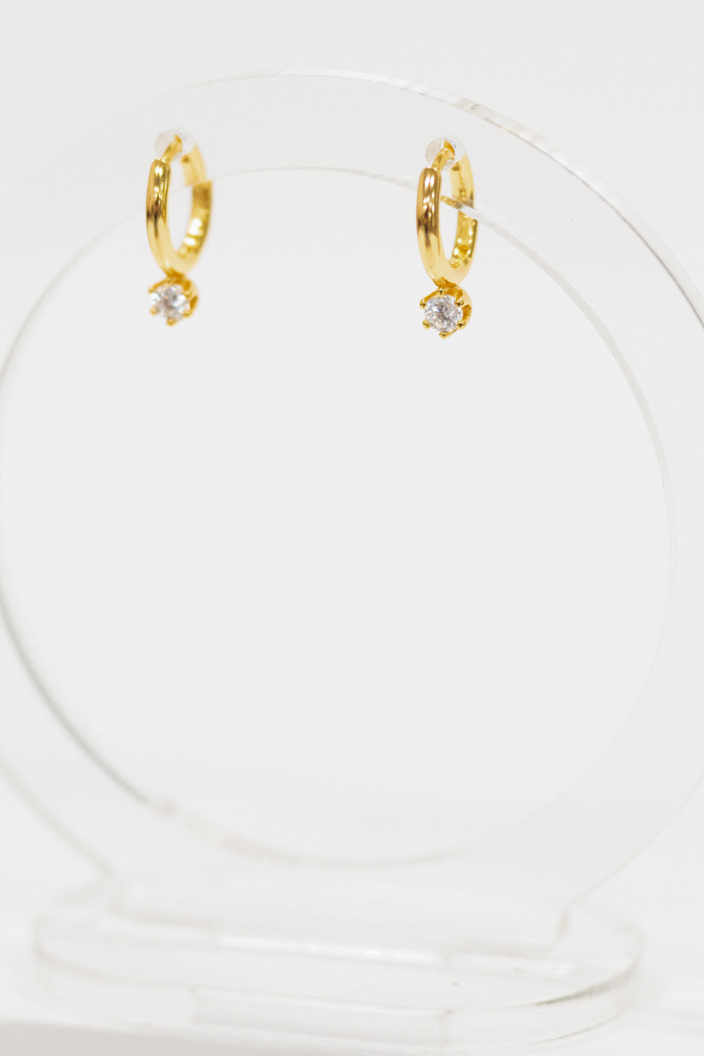 Gold hoop earrings with small cz stud on a white background