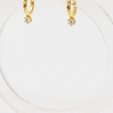 Gold hoop earrings with small cz stud on a white background