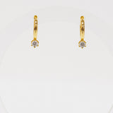 Gold hoop earrings with small diamonds on a white background