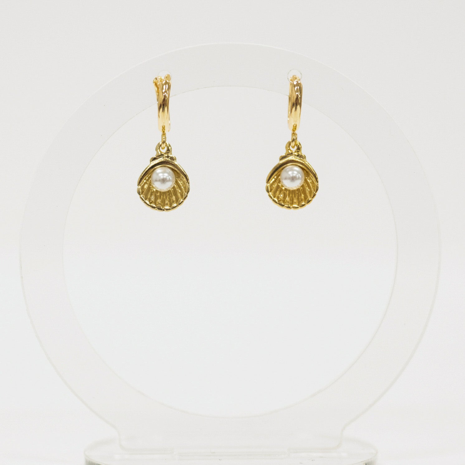 Gold shell earrings with pearl center on a white background