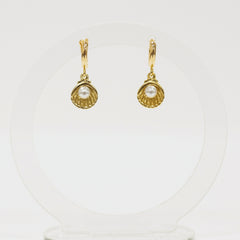 Gold shell earrings with pearl center on a white background