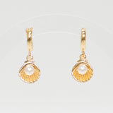 Gold shell earrings with pearl-like centers on a light gray background