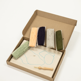 Box containing wooden tools and a thread on a white background