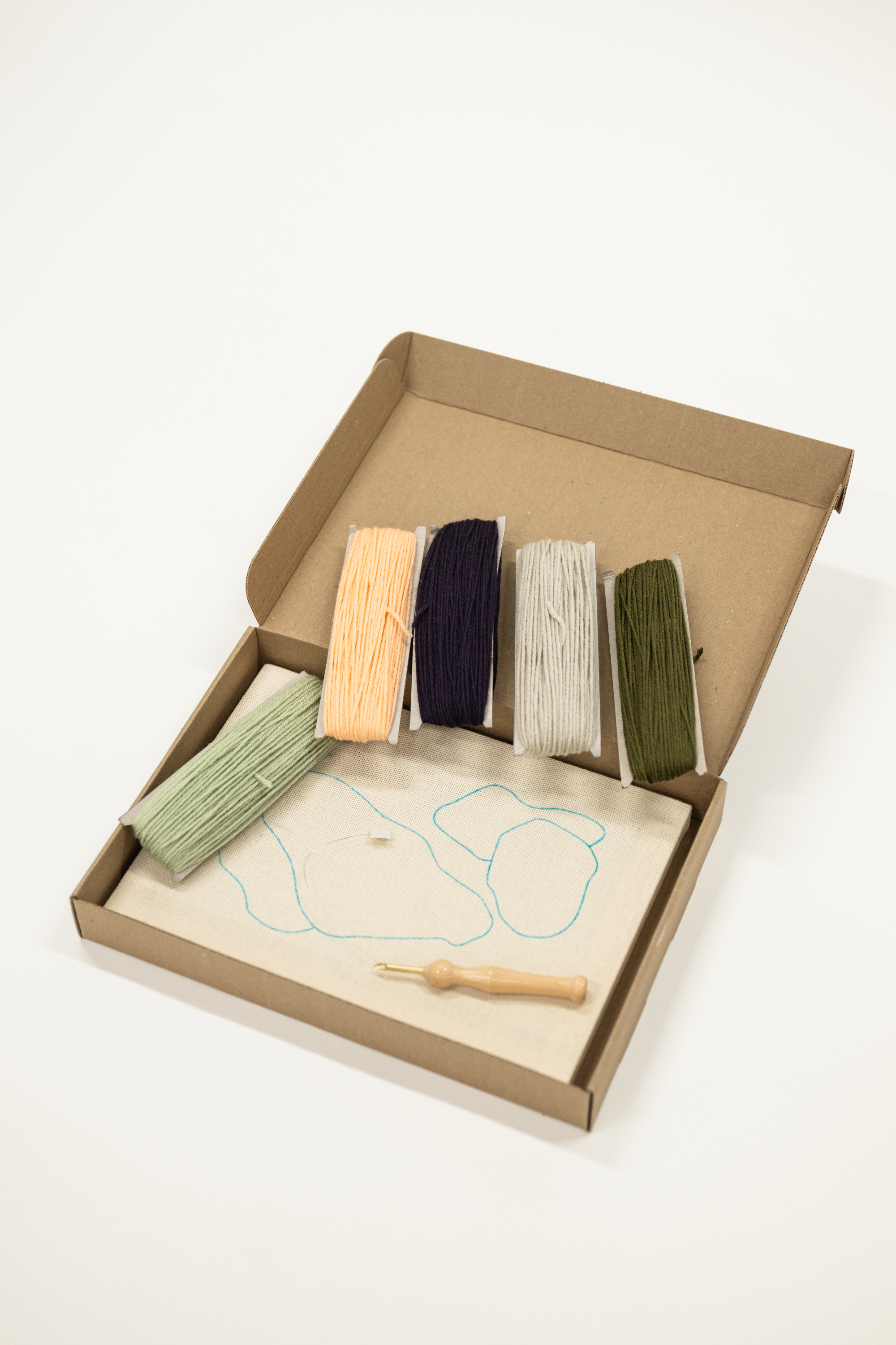 Box containing wooden tools and a thread on a white background