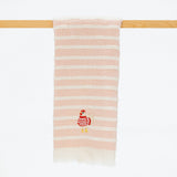 A soft pink and white striped bath towel with a small embroidered red-and-white bird character near the bottom, hanging from a light wood rod against a plain white background.