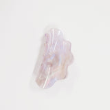 An organic-shaped resin hair claw clip with a pearlescent, iridescent finish showing soft lavender, pink, and white hues, set against a plain white background.