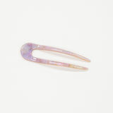 Iridescent hair clip on a light purple background