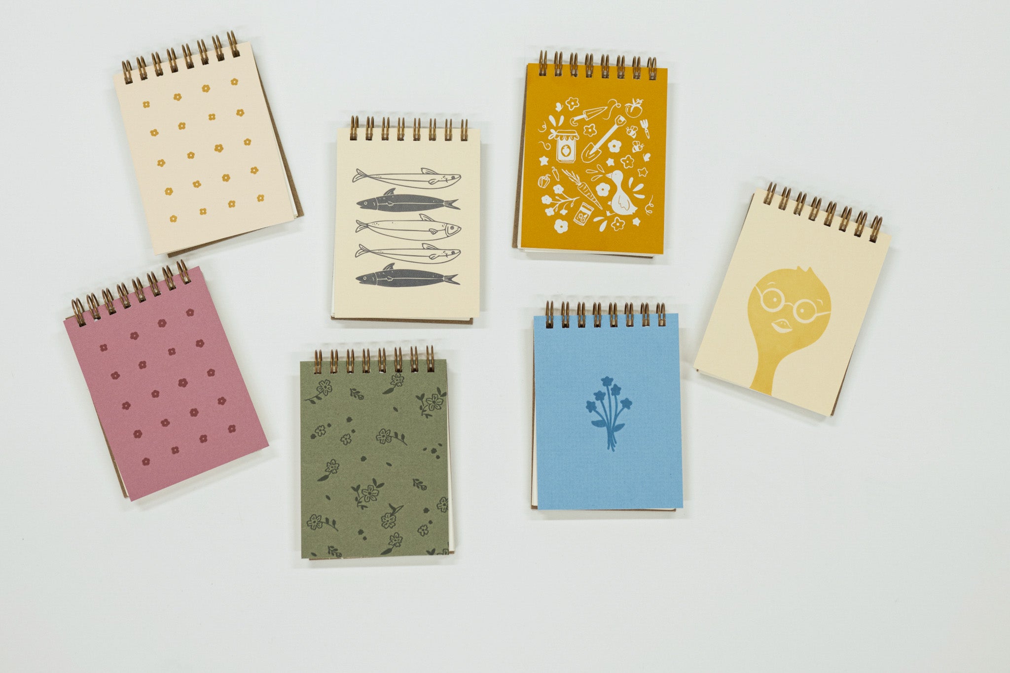 Set of small notebooks with various designs on a light gray background