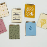 Set of small notebooks with various designs on a light gray background