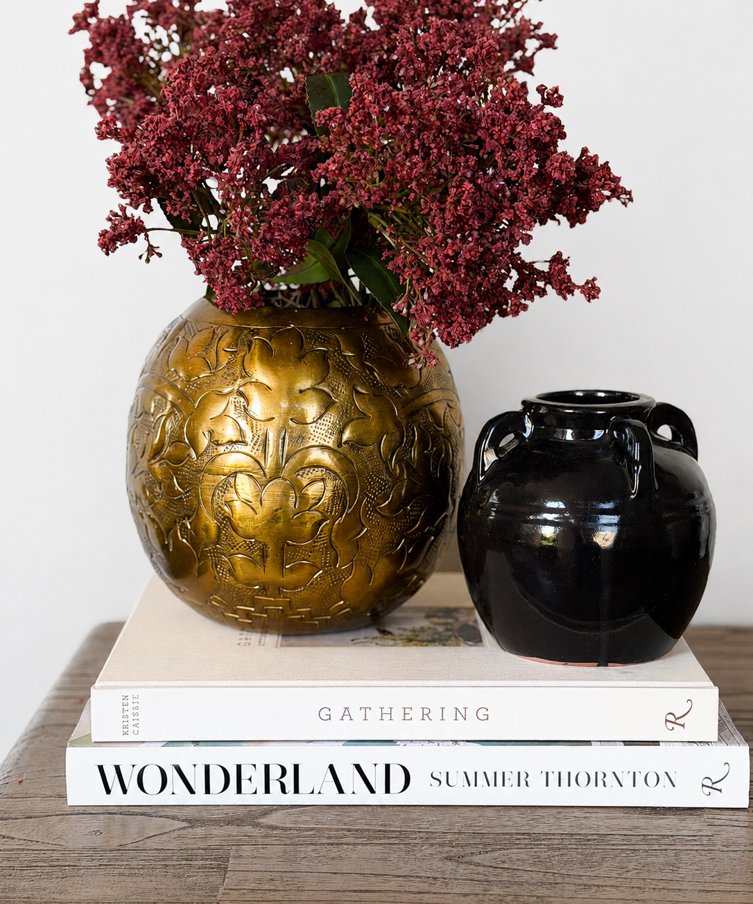 a vignette made of pressed bronze metal vase, glossy black vase, faux florals