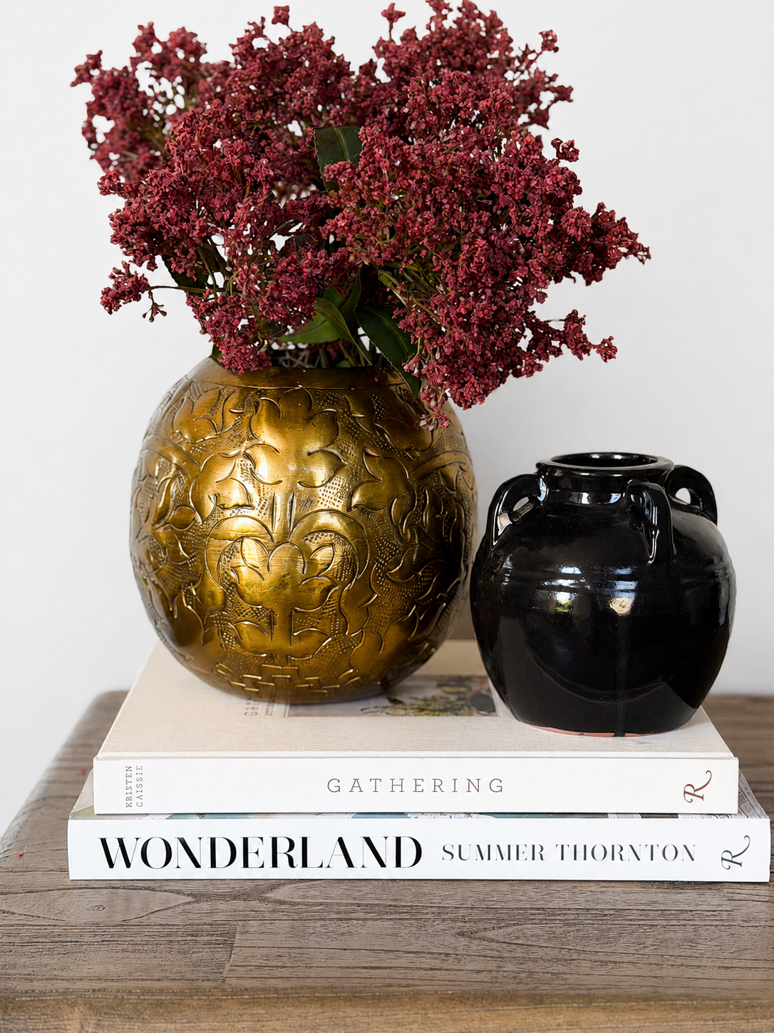 a vignette made of pressed bronze metal vase, glossy black vase, faux florals