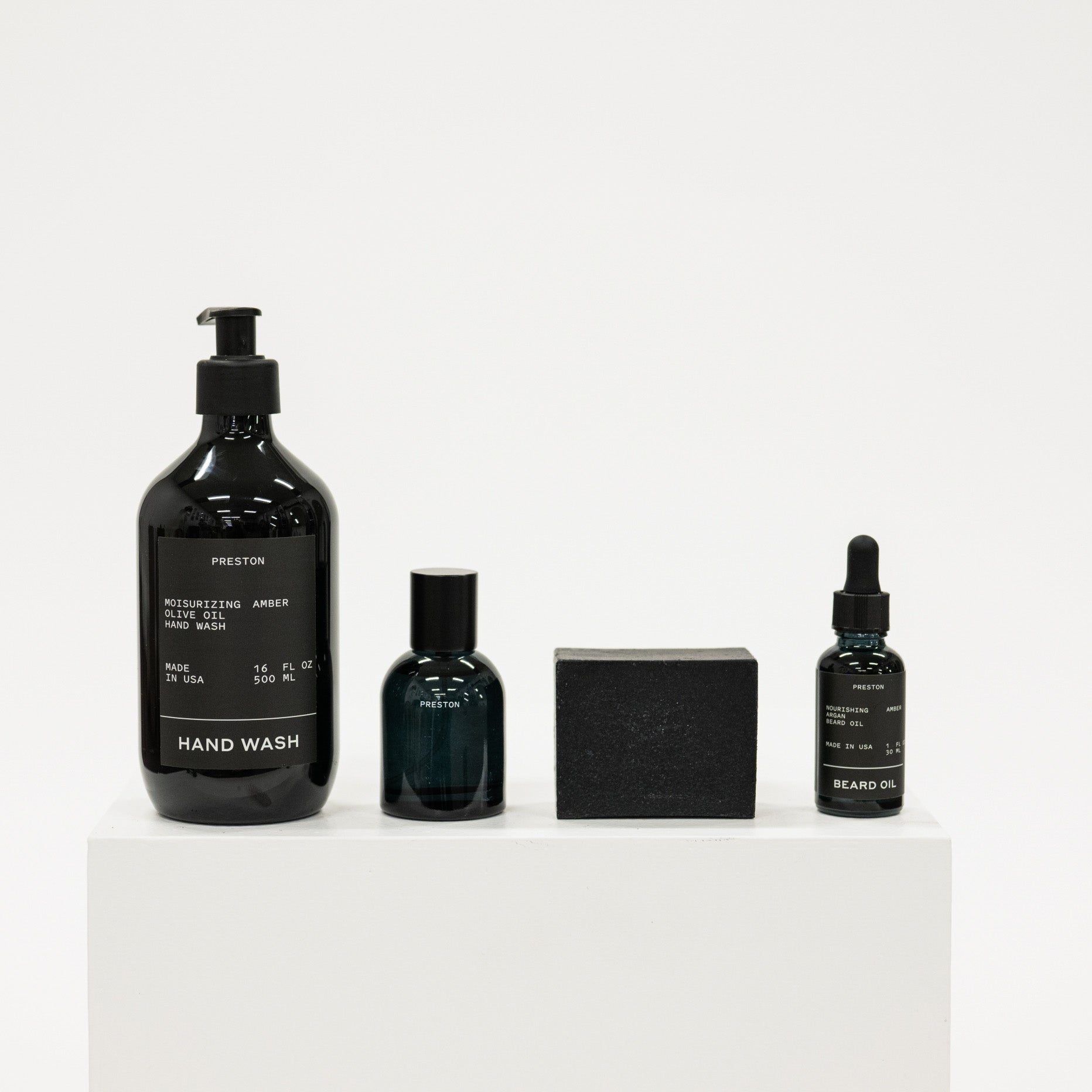 Set of grooming products including hand wash, beard oil, and other items on a white background
