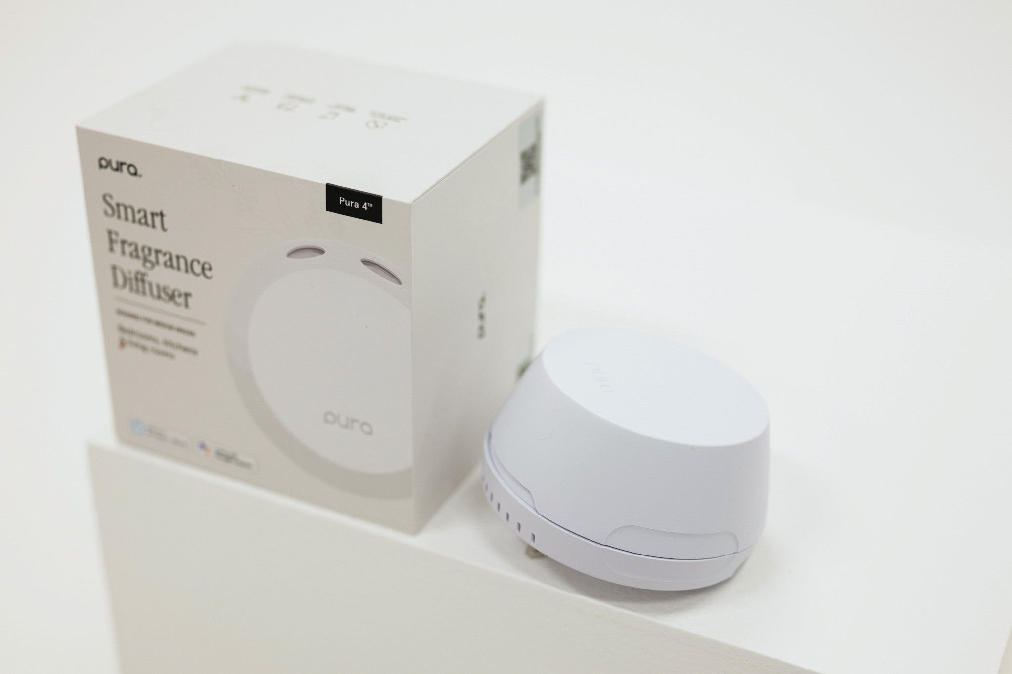 Pura smart fragrance diffuser with packaging on a white background