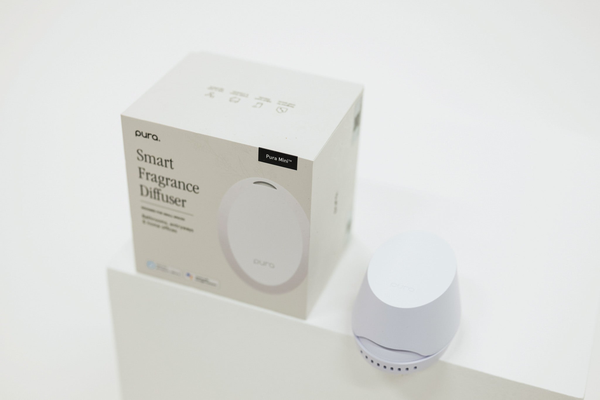 Pura smart fragrance diffuser with packaging on a white background