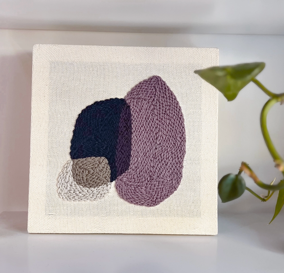 Textile art diy kit with knitted shapes on a plain background