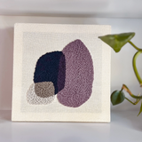 Textile art diy kit with knitted shapes on a plain background