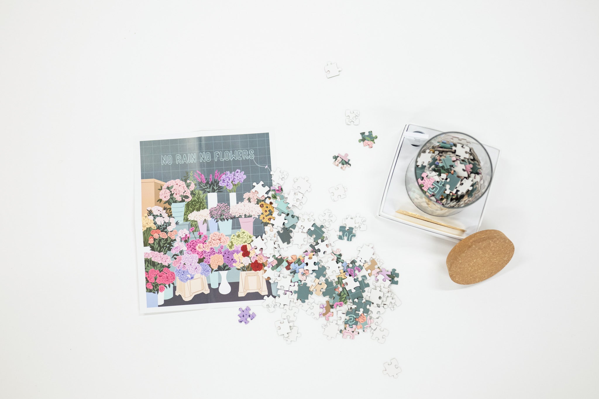 Floral-themed puzzle with pieces scattered on a white surface, accompanied by a box of additional pieces.